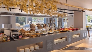 Un buffet proposant une variété de plats, une machine à café et des éléments décoratifs, comme des feuilles suspendues.
