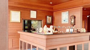 A reception area with a wooden counter, framed pictures on the walls, and a tiled floor. - Baan Karnjana Hotel Samui (Koh Samui)