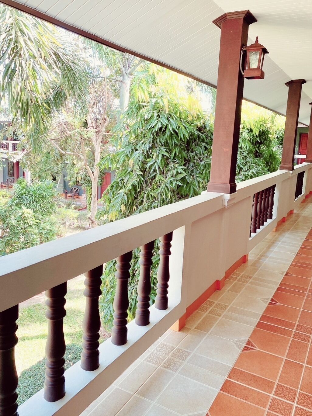 A covered balcony with a tiled floor and a railing.