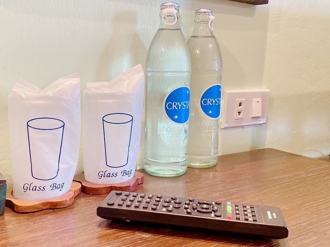 Eine Fernbedienung, zwei Glaskerzen und zwei Flaschen Crystal-Wasser auf einer Holztischfläche.