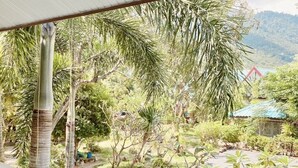 A view from a balcony with a railing, overlooking a garden with various plants and a small pool. - Baan Karnjana Hotel Samui (Koh Samui)