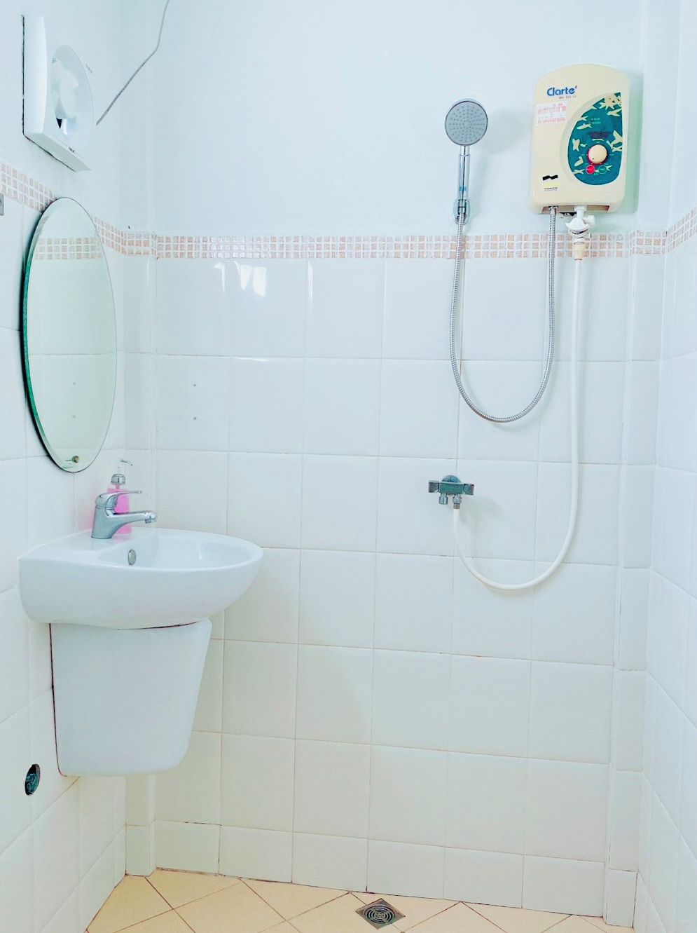 Een badkamer met een wit wastafelmeubel, een spiegel, een douche met bedieningspaneel en een betegelde vloer.