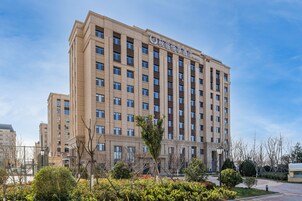 Un hotel de varios pisos con fachada color crema, numerosas ventanas y un letrero que indica que es un hotel.