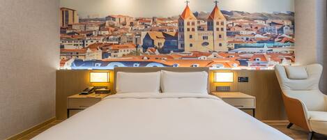 Habitación de hotel con una cama grande, mesitas de noche con lámparas, una silla y un mural con una vista urbana en la pared.