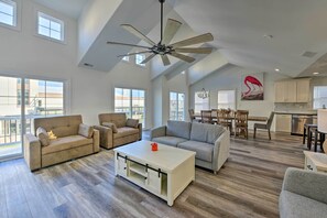 A spacious living area with a high ceiling, large windows, and a modern kitchen. - New-Build North Wildwood Home w/ Private Pool (North Wildwood)