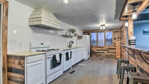 Uma cozinha moderna com armários brancos, fogão embutido e uma parede de destaque em madeira.