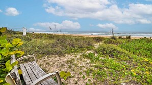 A beach with a wooden bench, a fence, and a view of the ocean. - Ormond Beach Retreat w/ Deck - Steps to Ocean! (Ormond Beach)