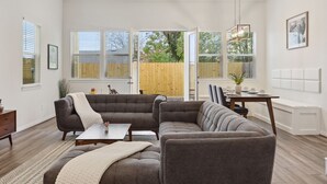 Ein geräumiges Wohnzimmer mit einem Ecksofa, einem Couchtisch und einem Essbereich mit Tisch und Stühlen.