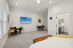 Ein Schlafzimmer mit einem Bett, einem Schreibtisch, einem Sessel, einer Couch und einem Bild an der Wand.