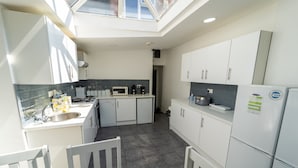 A compact kitchen with white cabinets, a microwave, a sink, and a table with chairs. - Studio Close to University of Birmingham (Birmingham)