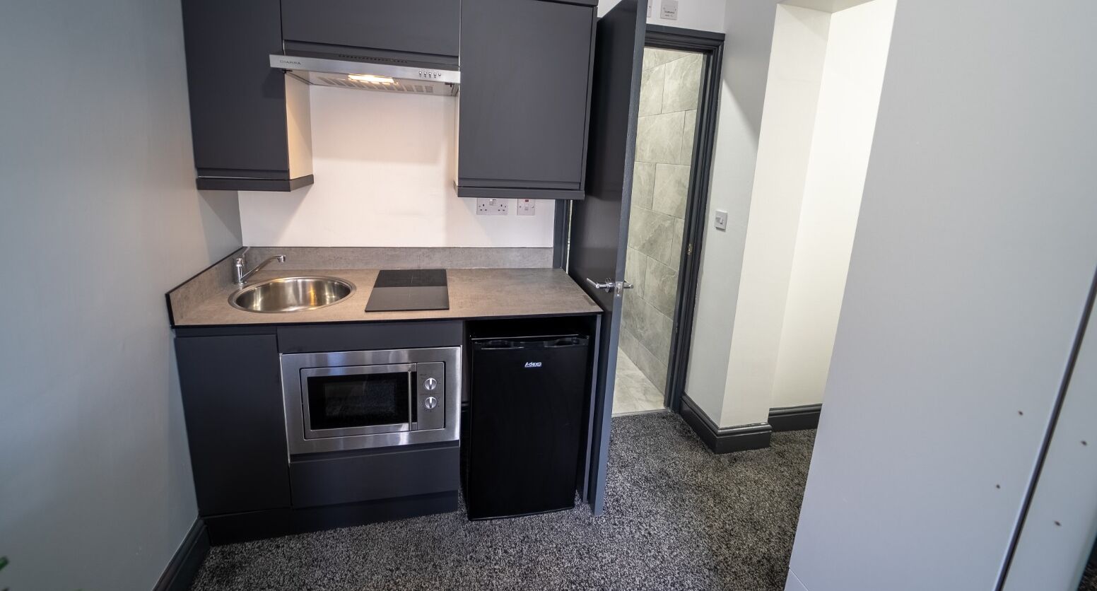 A compact kitchen with a stainless steel sink, an oven, and a dishwasher.