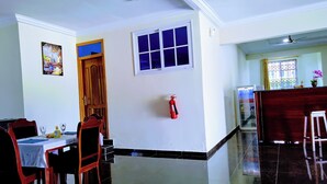 A dining area with a table, chairs, a fire extinguisher, and a window. - Renajoe Ejisu-Kubease (Kubease)