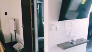 Una habitación con televisión integrada, una puerta y un estante pequeño.