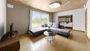 Una sala de estar moderna con un sofá modular, una mesa de centro redonda y un televisor sobre un mueble de madera.
