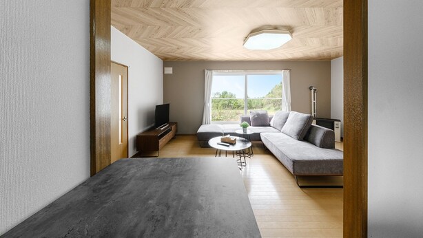 Una sala de estar moderna con techo de madera, un sofá gris, una mesita de centro pequeña y un televisor sobre un mueble de madera.