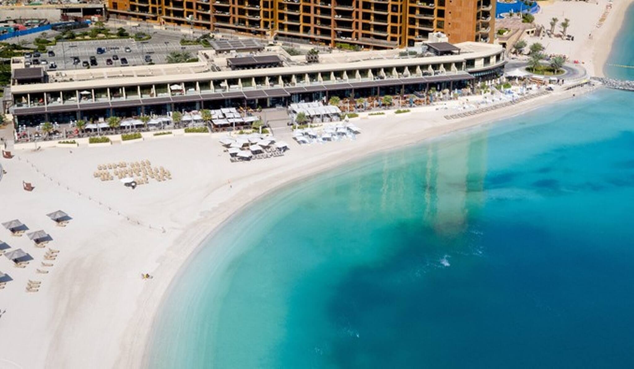 A coastal hotel with a beachfront promenade, multiple dining areas, and a poolside bar.