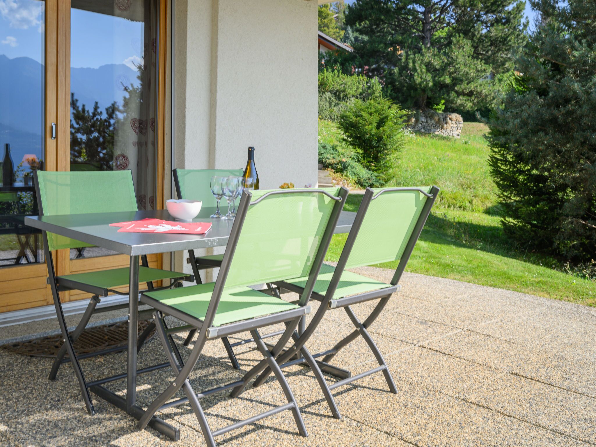 Een buiten eethoek met een tafel, stoelen, een fles en een kom.