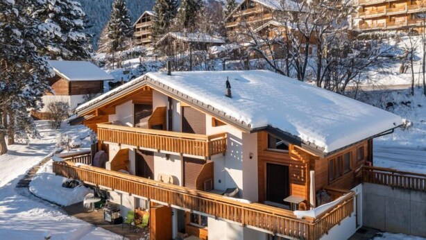 A two-story chalet with a balcony, wooden exterior, and snow-covered surroundings. - Plein Sud 3 by Interhome (Ovronnaz)