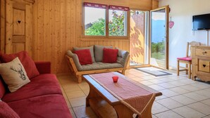 A cozy room with wooden walls, a sofa, a table, and a TV. - Plein Sud 3 by Interhome (Ovronnaz)