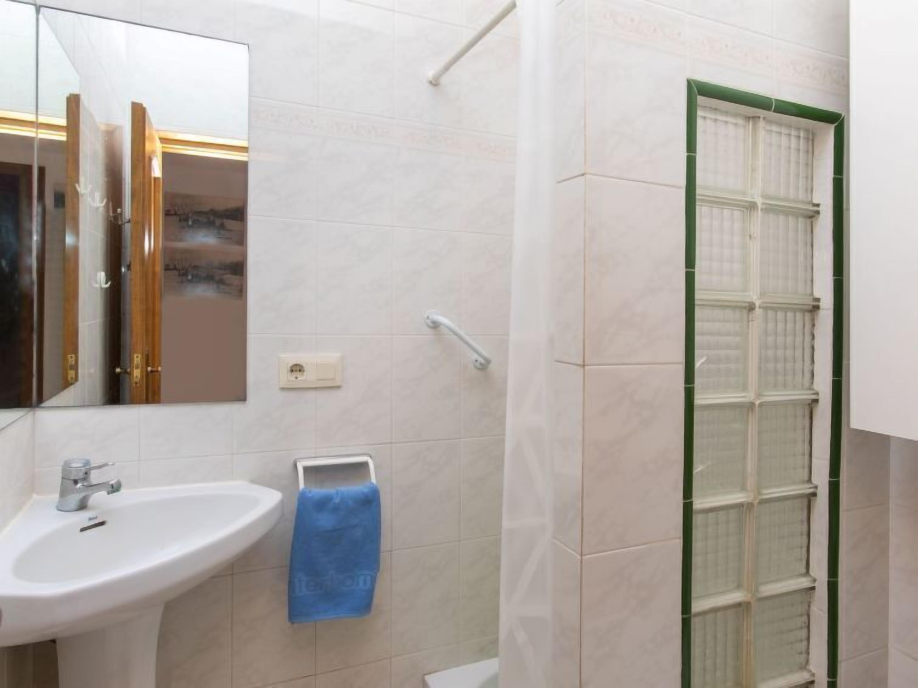Une salle de bain avec un lavabo blanc, un miroir et une douche en verre.