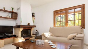 Una sala de estar con televisión, chimenea, sofá y ventana con persianas.