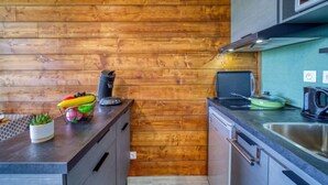 Una cocina compacta con paneles de madera, un lavamanos de acero inoxidable y electrodomésticos modernos.