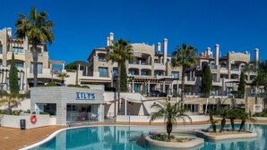 A hotel with a pool, multiple balconies, and a sign for 'LILY'S'.