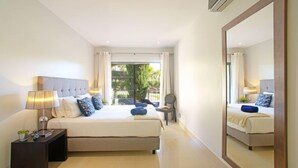 Un dormitorio moderno con una cama grande, una mesita de noche, una silla y un espejo amplio.