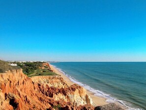 Paisagem costeira com falésias e uma praia.
