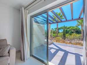 Habitación moderna con puerta de vidrio corredera que da a un balcón exterior con vistas a la vegetación y un cielo despejado.