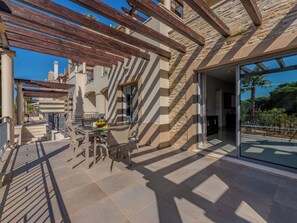 A patio area with a table and chairs, a pergola, and a view of the surrounding landscape. - Pine Hills Rubi by Interhome (Vilamoura)