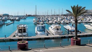 A marina with numerous boats docked, a clear blue sky, and a palm tree in the foreground. - Pine Hills Pérola by Interhome (Vilamoura)
