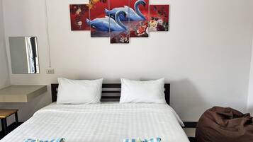 A hotel room with a large bed, two pillows, a brown bean bag, and a wall art piece depicting a swan and flowers.