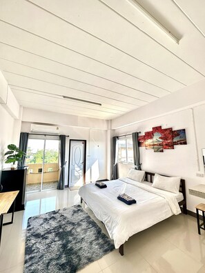 A modern bedroom with a large bed, a desk, a chair, a potted plant, and a balcony with a view. - MY HOME SAI4 (Sam Phran)