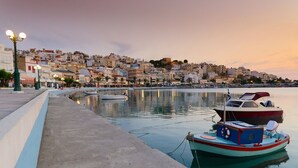 Una veduta sul lungomare con barche ormeggiate, un passeggiata e edifici sullo sfondo.