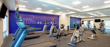 Une salle de sport équipée de tapis de course, d’appareils elliptiques et de vélos d’appartement.