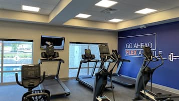 Un centre de remise en forme équipé de tapis de course, de vélos elliptiques et d’un mur orné de messages motivants.