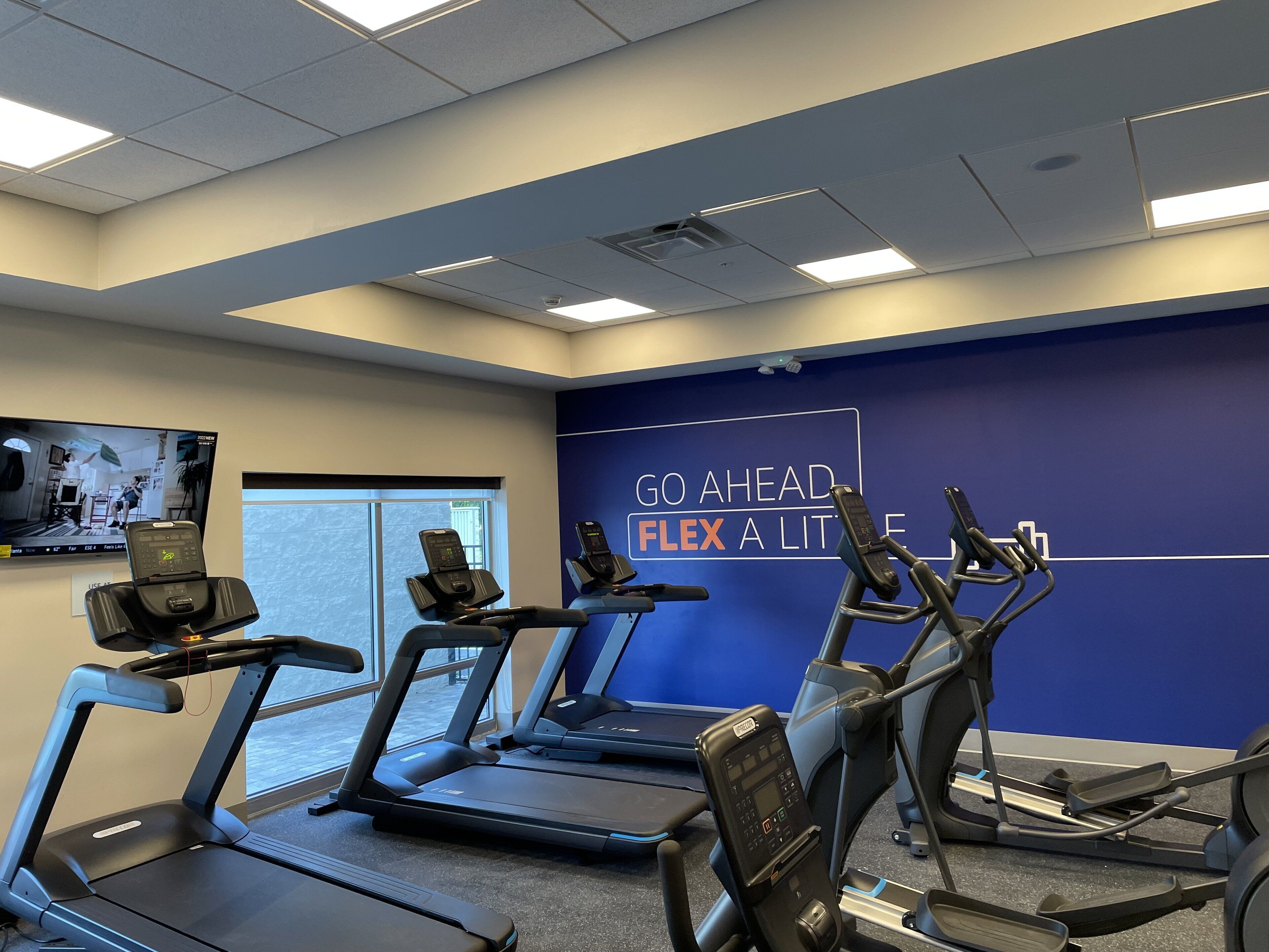 A fitness room with treadmills, exercise bikes, and a motivational wall.