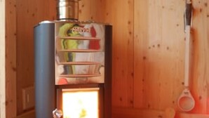 A wood-burning stove in a wooden cabin with a metal door, a small window, and a wooden bucket on the floor. - THE BOZZLE, THE COMBA of Aosta (Valle d'Aosta)