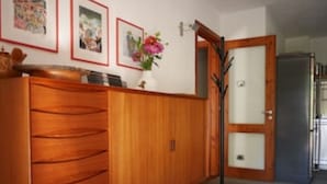 Um guarda-roupa de madeira com várias gavetas, uma porta com painéis de vidro e um vaso com flores na parede.