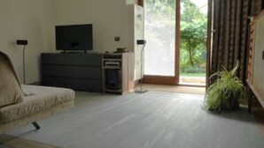 Uma sala de estar com sofá, televisão, armário e planta.