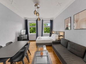 Ein modernes Hotelzimmer mit Bett, Sofa, Esstisch und Stühlen.