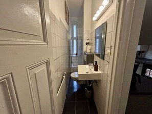 Une petite salle de bain avec un lavabo blanc, un miroir et une fenêtre.
