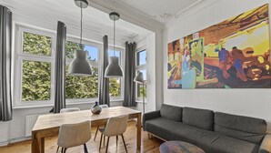 Una sala moderna con una mesa de comedor de madera, un sofá gris y un cuadro abstracto colorido en la pared.