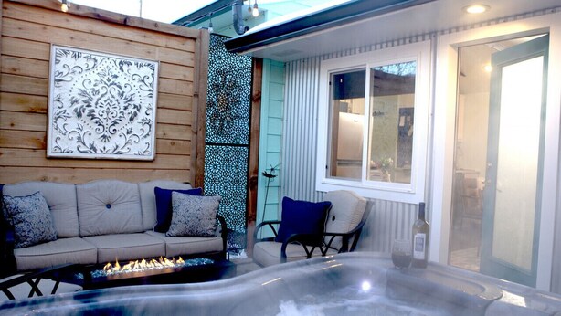 A cozy outdoor seating area with a sofa and chairs, a hot tub, and a decorative wall panel. - Hot Tub Studio! Sparkling Clean, Close to Oldtown. (Loveland)