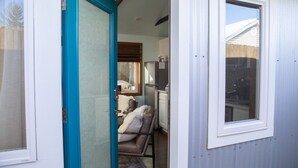 A compact kitchen with a refrigerator, a dining area with a table and chairs, and a small window. - Hot Tub Studio! Sparkling Clean, Close to Oldtown. (Loveland)