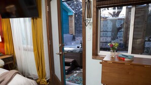 A hotel room with a bed, a desk, a window with a view of the outside, and a door leading to a balcony. - Hot Tub Studio! Sparkling Clean, Close to Oldtown. (Loveland)