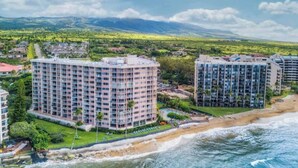 Un hotel costaner amb diversos edificis alts, una platja i un paisatge de muntanyes al fons.