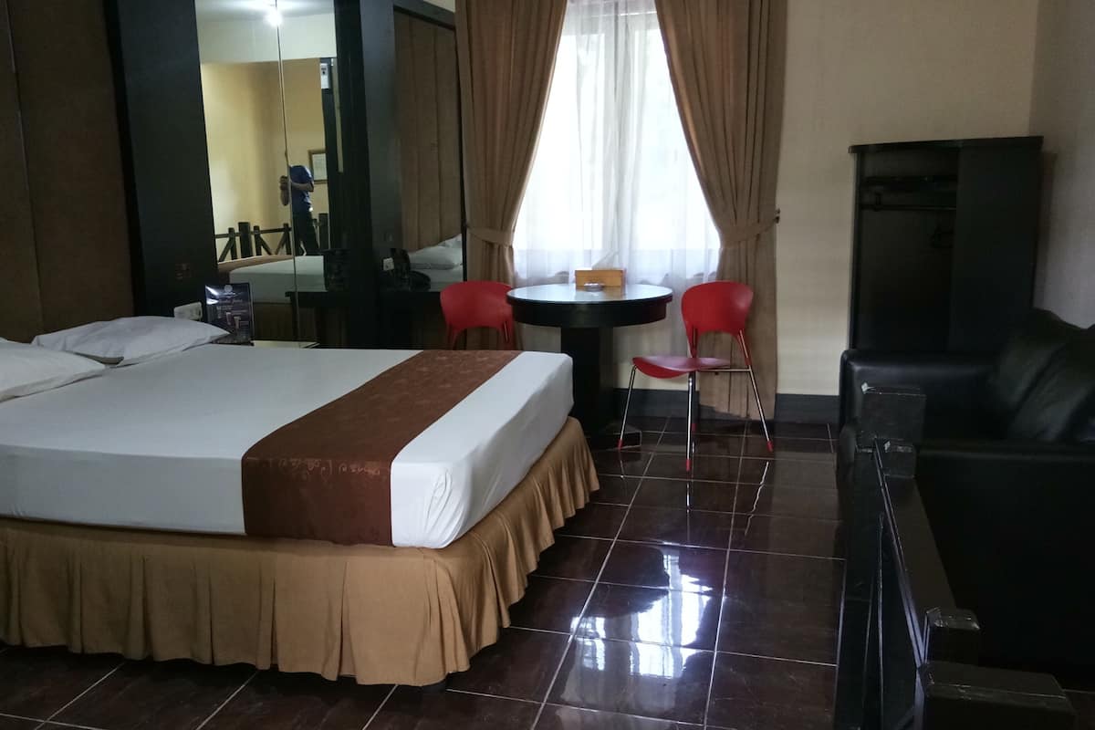 Une chambre d’hôtel avec un grand lit, un bureau avec une chaise, une petite table avec une chaise et un téléviseur.