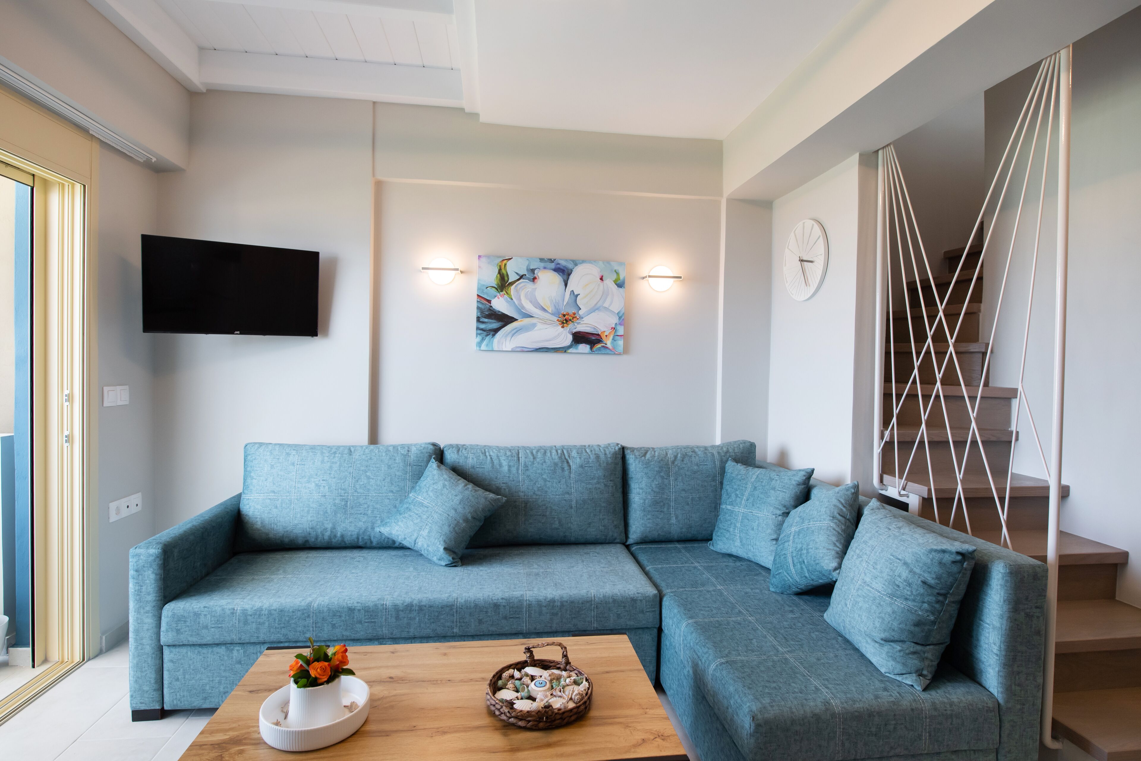 Una sala de estar moderna con un sofá seccional azul, un televisor de pantalla plana y un adorno en la pared.